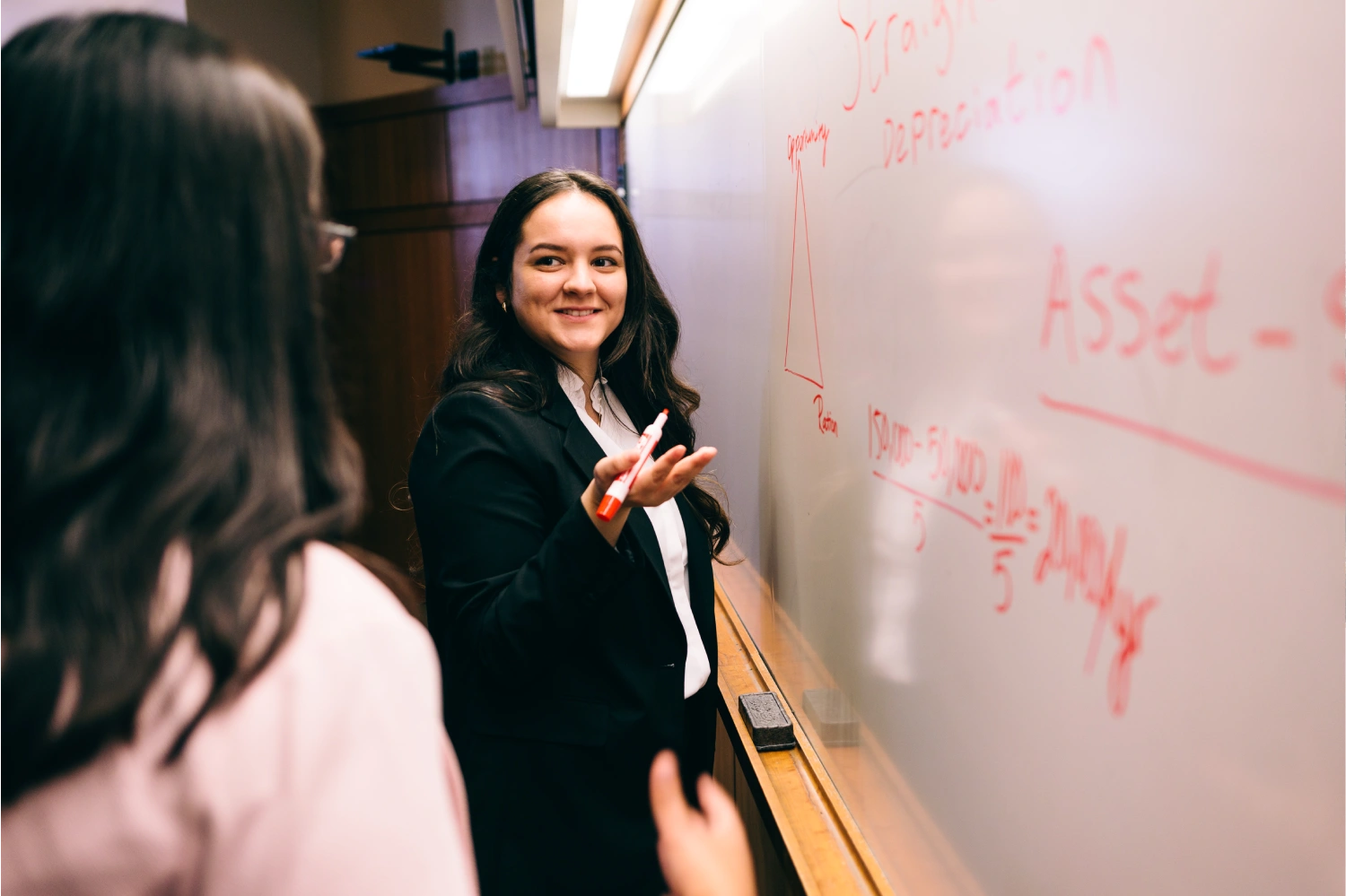 Graduate student explaining concept at whiteboard