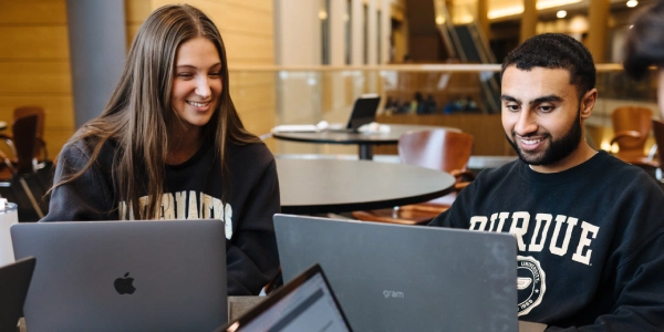 two students working together on laptops