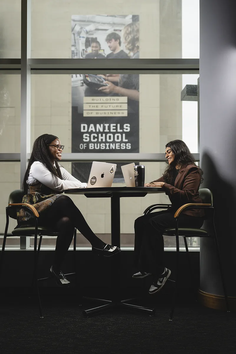 Two female students talking with the Krannert building in the background