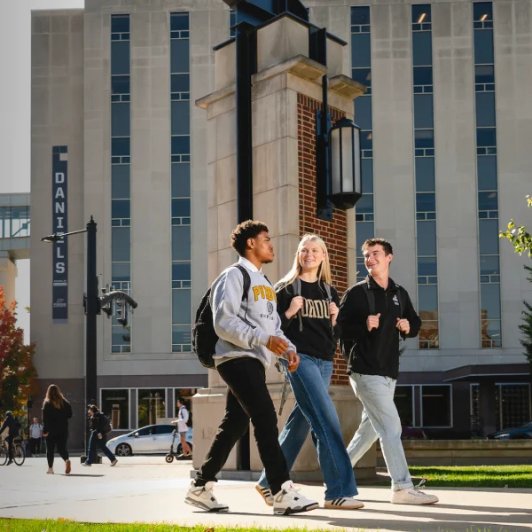 Three students walking in front of Daniels School building