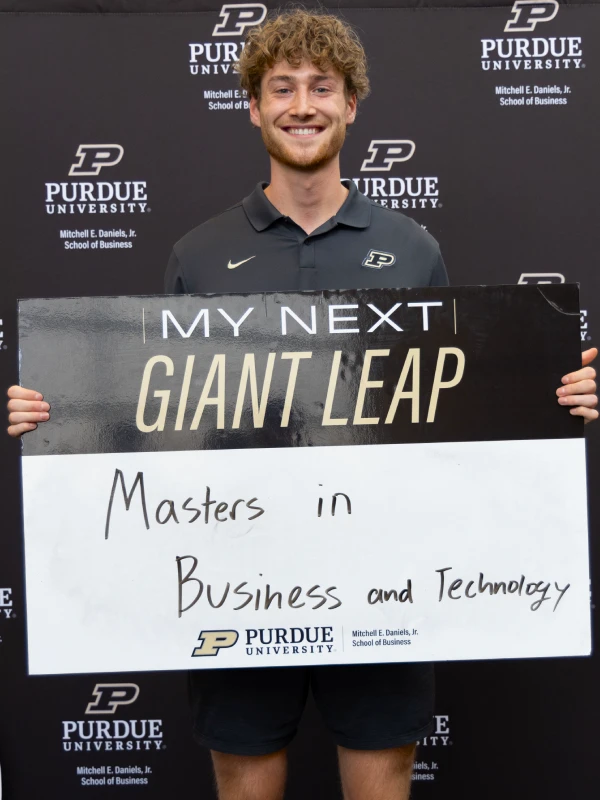 Owen Mahin holding a sign that reads 'My Next Giant Leap... Master of Business & Technology'