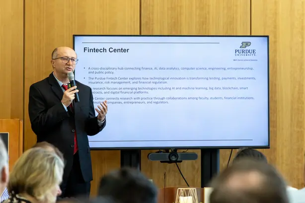 Deniz Yavuz speaks to audience in front of slides about the Fintech Center