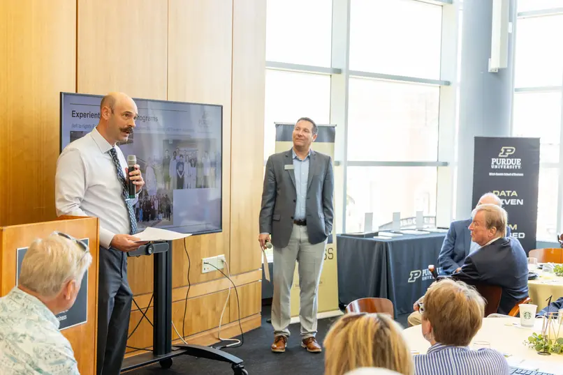 Professor holding paper presents to audience